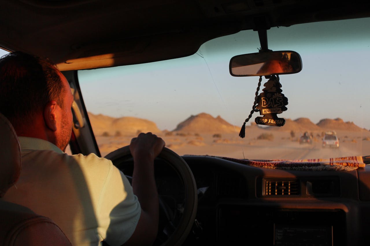 A man driving through a scenic desert landscape at sunset, capturing adventure and travel.